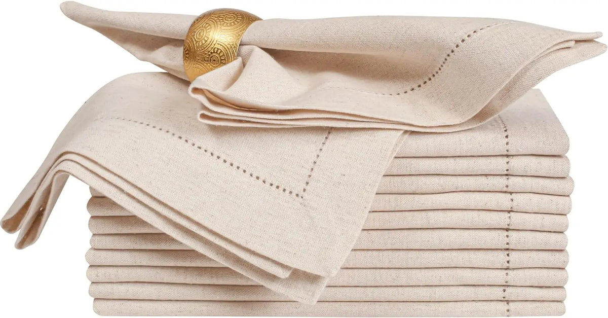 Serviettes de table en lin beige avec un anneau de serviette doré orné de motifs décoratifs.