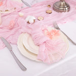 Une table de fête élégante avec des assiettes blanches, une serviette en tissu rose pastel, et une belle fleur en guise de décoration.