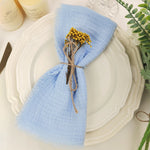 Détail de la table de dîner avec une serviette en lin bleu et un bouquet de fleurs jaunes attaché avec de la ficelle.