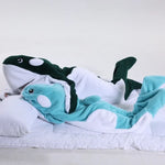 L'image montre des jouets en peluche en forme de différents types de poissons, dans un lit douillet, suggérant un concept ludique et apaisant.