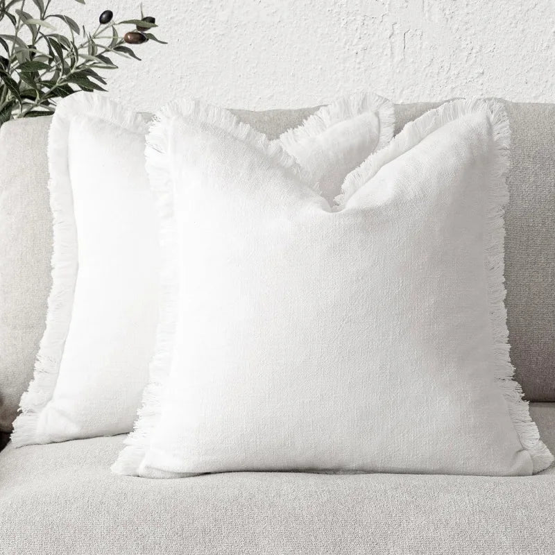 Deux oreillers blancs moelleux posés sur un canapé gris dans un intérieur cosy.