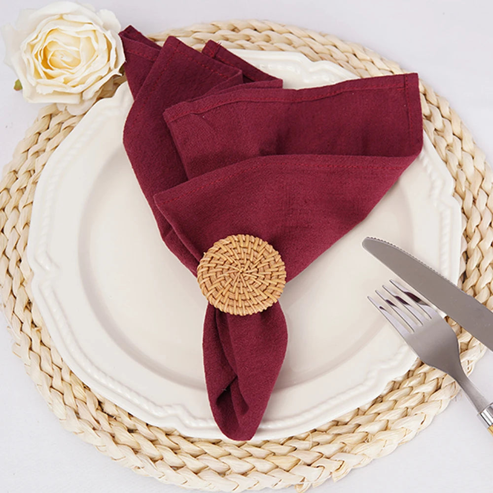 Mise en place élégante d'une table avec une serviette de table bordeaux, une rose blanche et des accessoires de table.