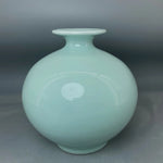Vase en céramique bleu-vert opaque avec un motif circulaire et des points incrustés.