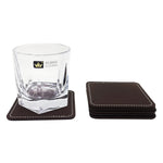Un verre à whisky élégant avec un ensemble de sous-verres en cuir marron.