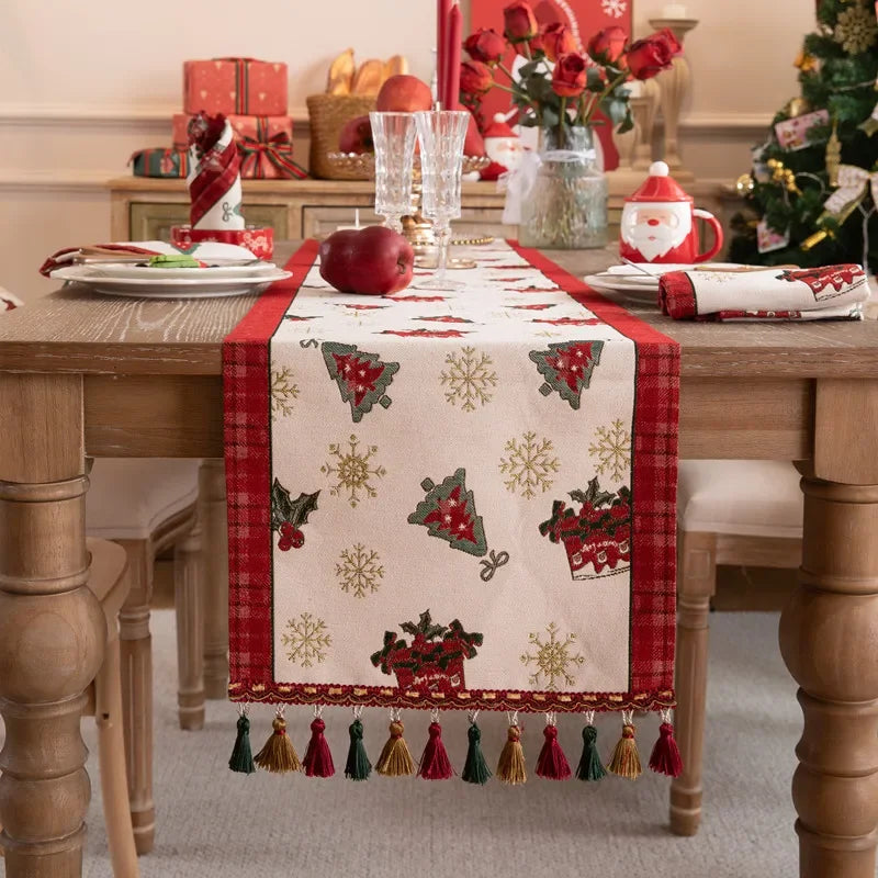 Une table de Noël joliment décorée avec des motifs d'arbres et de flocons de neige sur un chemin de table rouge.