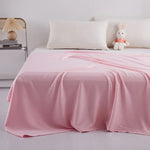 Une couverture rose pastel douillette et confortable recouvre ce lit, avec un coussin blanc et une peluche de lapin posés sur le côté, créant une ambiance reposante et accueillante.