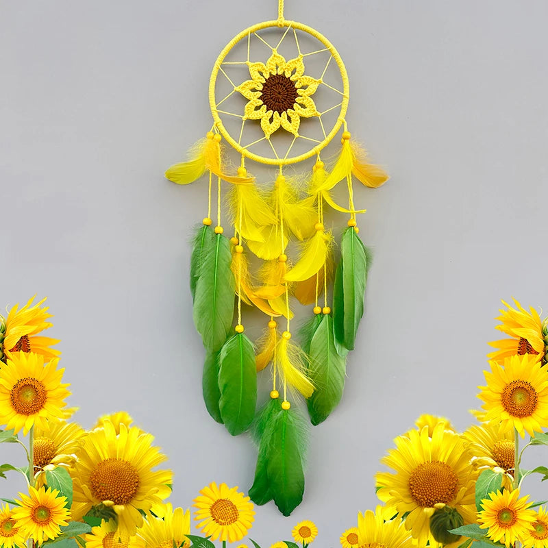 Un capteur de rêve décoratif avec un grand tournesol au centre, entouré de plumes jaunes et vertes, suspendu dans un cercle doré. Autour de l'objet, on voit de magnifiques tournesols jaunes.