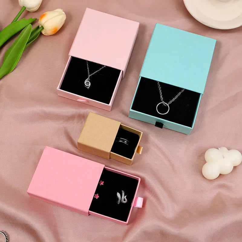 Boîte papier ouverte avec colliers et boucles d'oreilles à l'intérieur