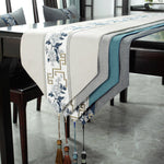 Chemin de table orné de motifs floraux bleus et d'un motif grec doré, accompagné de décorations pendantes assorties, créant une ambiance élégante et raffinée dans cette salle à manger.