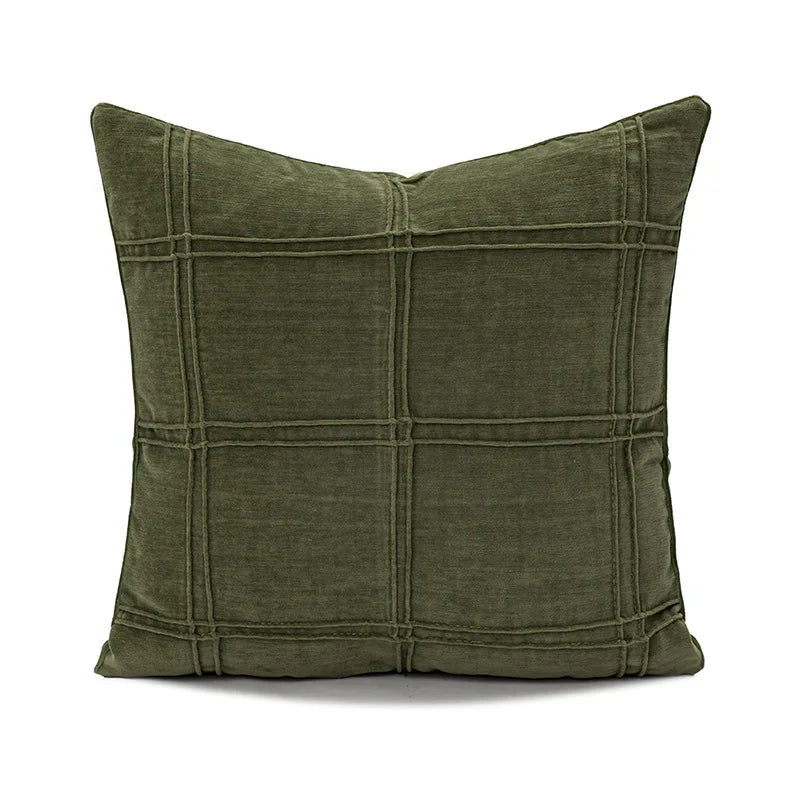 Un coussin vert foncé avec des lignes noires formant un motif de carreaux.