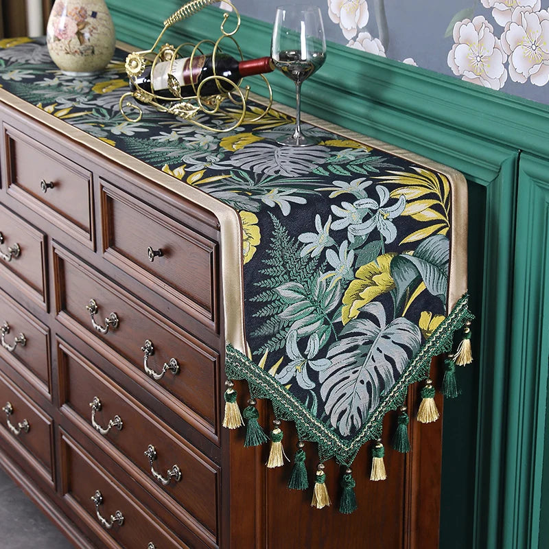 Une élégante décoration murale peinte à la main ornée de motifs floraux tropicaux sur fond sombre, posée sur une belle commode en bois sombre avec des ustensiles de vin.
