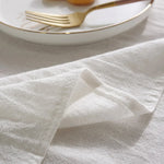 L'image montre une assiette avec des couverts en métal doré posés sur un linge de table blanc et froissé, suggérant une ambiance élégante et minimaliste pour un repas.