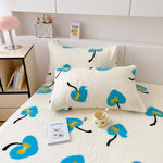 Ensemble de literie confortable avec motif de fleurs bleues et jaunes sur un fond blanc, composé de deux oreillers et d'un dessus de lit, offrant un style décoratif agréable pour une chambre.