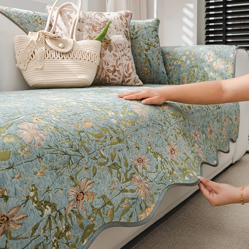 Un lit muni d'une couverture et de coussins aux motifs floraux délicats et de couleurs pastel, avec un sac en filet beige posé à côté, créant une atmosphère relaxante et harmonieuse dans cette pièce.