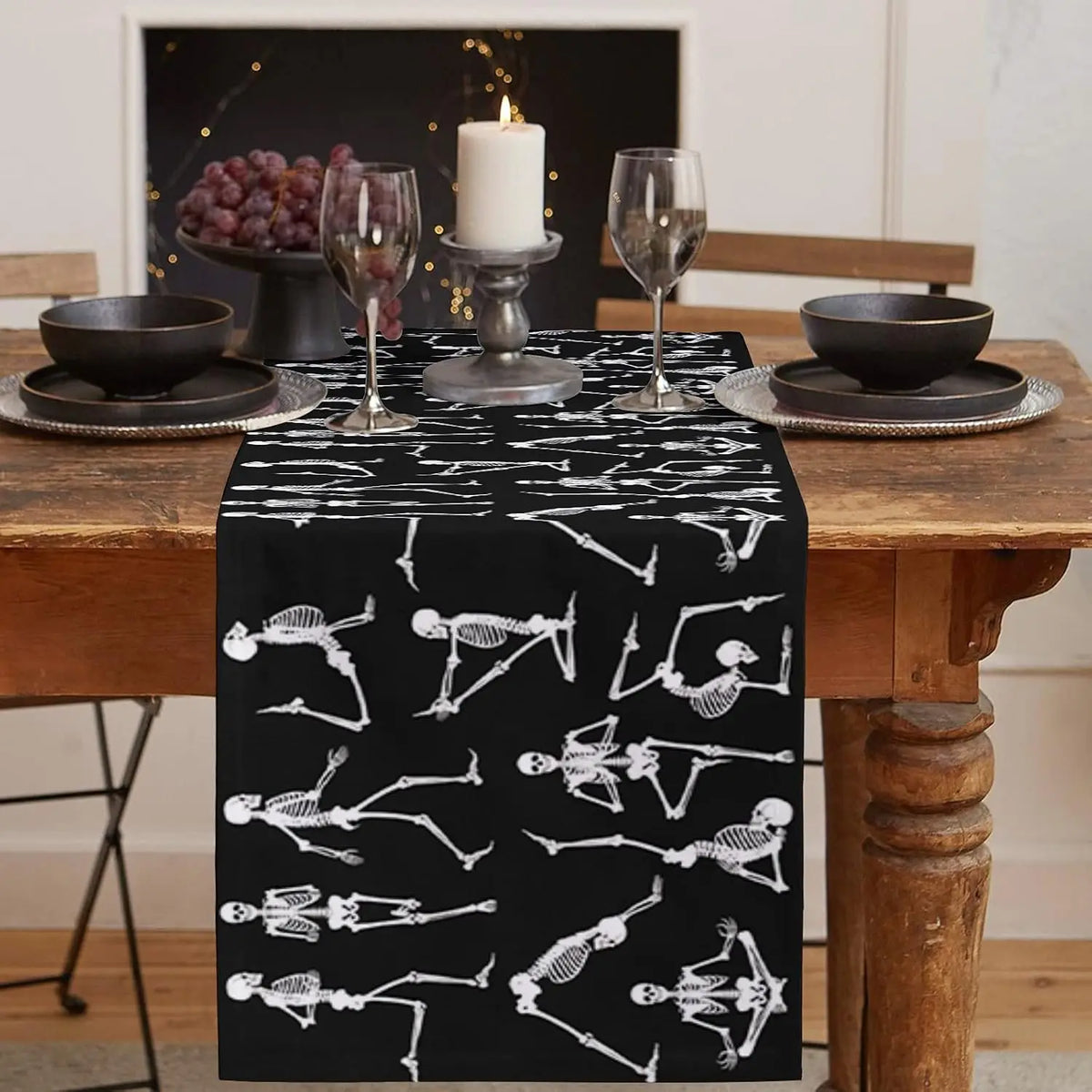 Une belle table de fête avec des verres à vin, une bougie allumée et des os de squelette imprimés sur un chemin de table sombre, créant une ambiance mystérieuse et élégante.