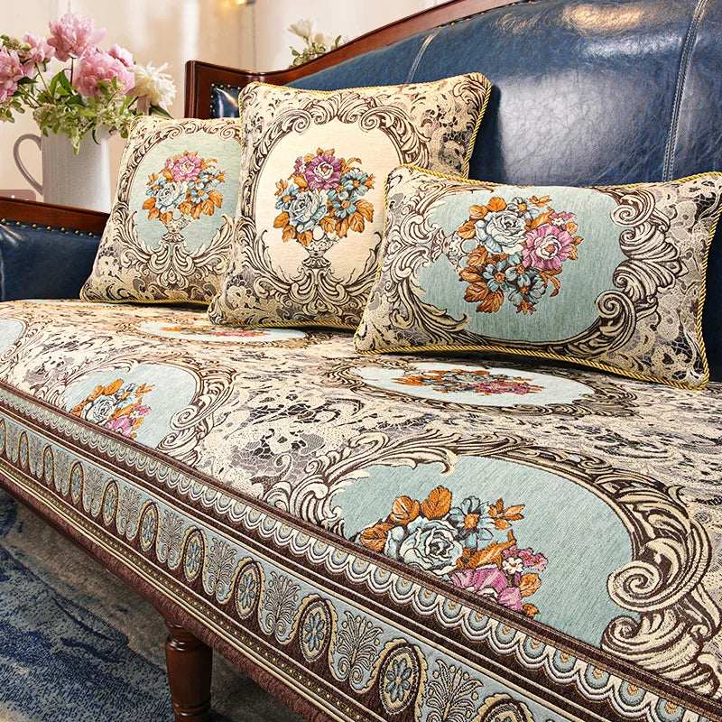 Cet image montre un beau canapé en cuir bleu foncé avec des coussins et une couverture décorés de motifs floraux élégants dans des tons pastel.