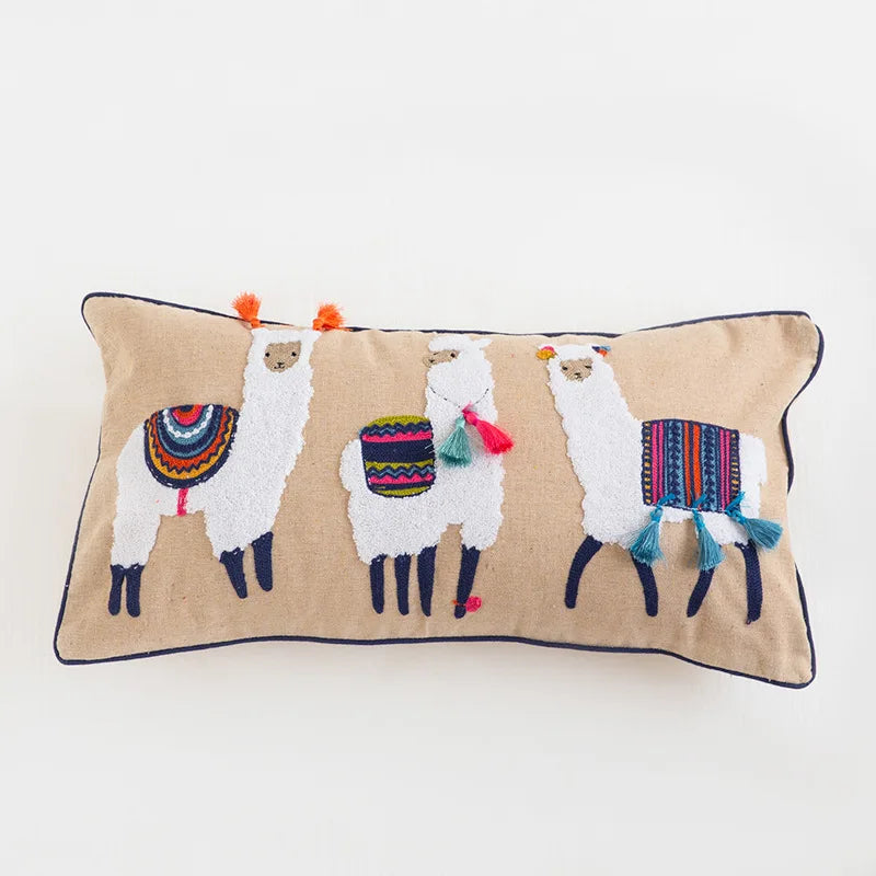 Cette image montre un coussin décoratif avec un motif coloré de lamas sur un fond beige.