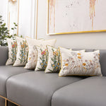 Une pièce élégante et apaisante, avec un canapé gris et des coussins ornés de motifs floraux colorés, créant une atmosphère chaleureuse et invitante.