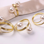 Des bagues dorées décorées de perles blanches brillantes, créant un élégant accessoire de mode.