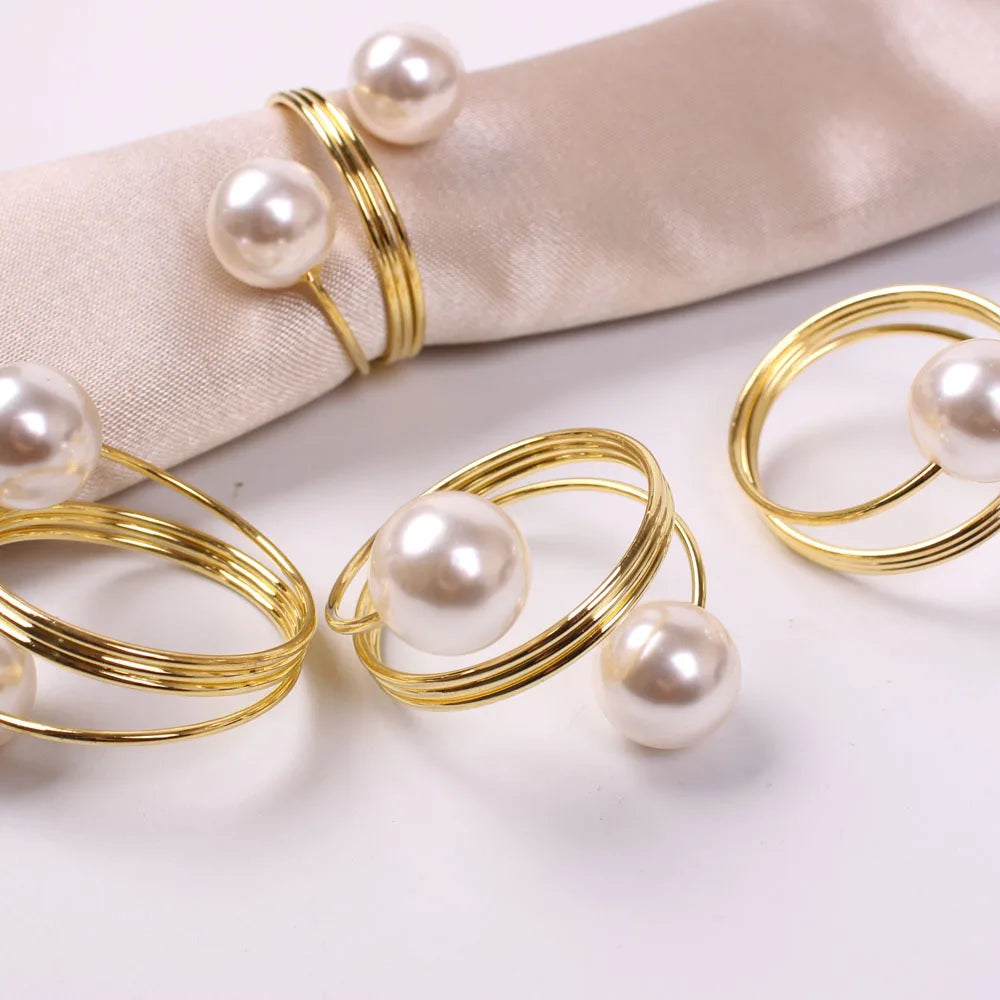 Des bagues dorées décorées de perles blanches brillantes, créant un élégant accessoire de mode.
