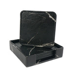 Élégants sous-verres en marbre noir, élégamment rangés dans une boîte assortie, offrant une touche de sophistication à toute table.