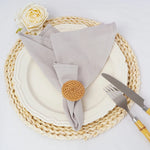Une magnifique décoration de table avec une assiette blanche, une serviette en lin gris, une rose blanche et des couverts en métal.