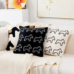 Des coussins décoratifs de couleurs sombres et contrastées, ornés de motifs de silhouettes animales, apportent une touche moderne et graphique à l'ambiance du salon.