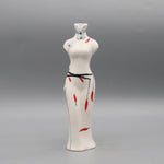 Figurine féminine en porcelaine blanche décorée de motifs floraux bleu ciel et de détails rouges.