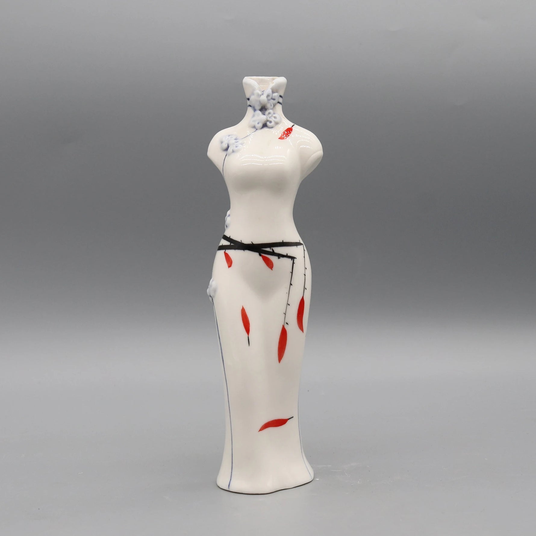 Figurine féminine en porcelaine blanche décorée de motifs floraux bleu ciel et de détails rouges.