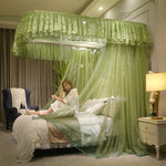 La photo montre une chambre à coucher élégante avec un lit à baldaquin vert orné de rideaux et de dentelle, mettant en scène une jeune femme assise sur le lit dans une robe blanche.