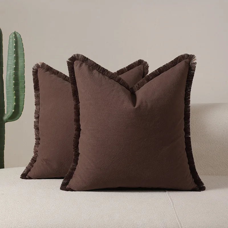 Coussins décoratifs carrés marron foncé avec bordures frangiées, parfaits pour une décoration intérieure chaleureuse et moderne.