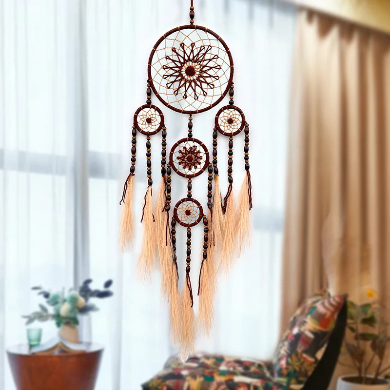 Magnifique capteur de rêves artisanal avec motifs floraux, perles et plumes, suspendu devant une fenêtre donnant sur un intérieur douillet.