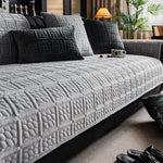 Une vaste causeuse gris foncé, ornée de motifs géométriques élégants, se trouve dans un salon cosy et bien aménagé.