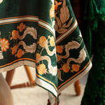 Une robe longue aux motifs floraux complexes et élégants dans des tons de vert et d'orange.