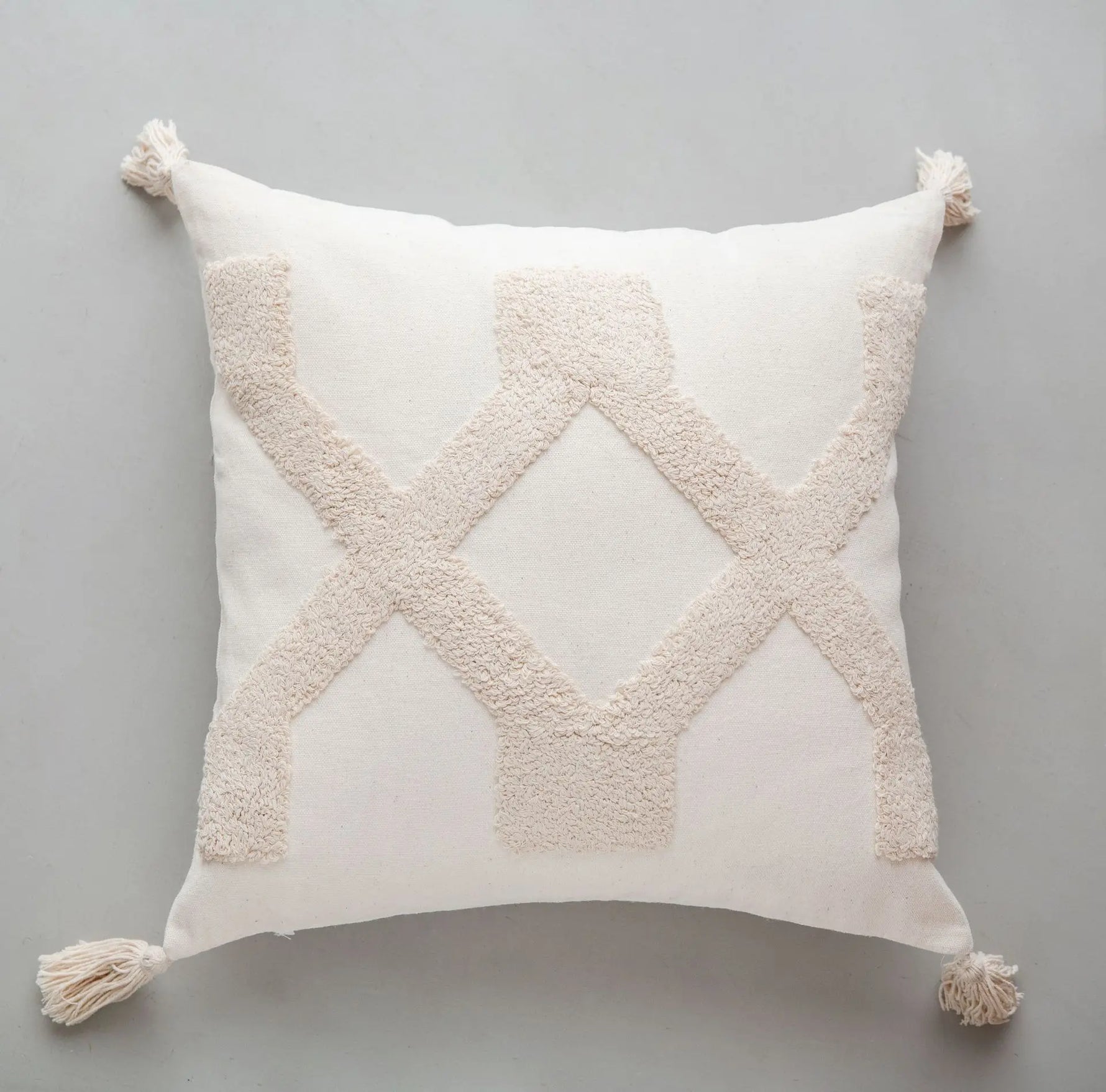 Coussin décoratif blanc avec des motifs en relief en forme de losanges en beige.