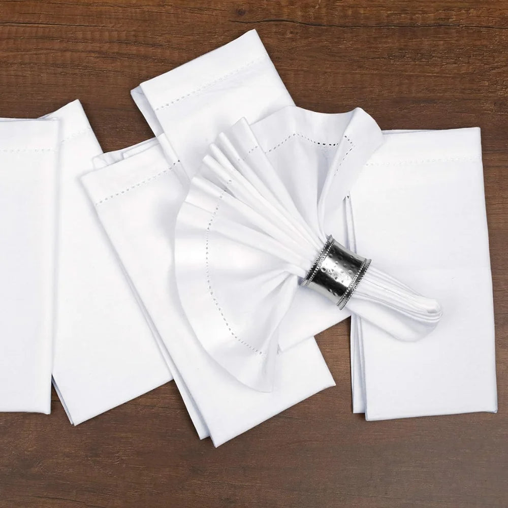 Des serviettes blanches soigneusement pliées et une cuillère en acier brillante sur une surface en bois, créant une composition épurée et élégante.