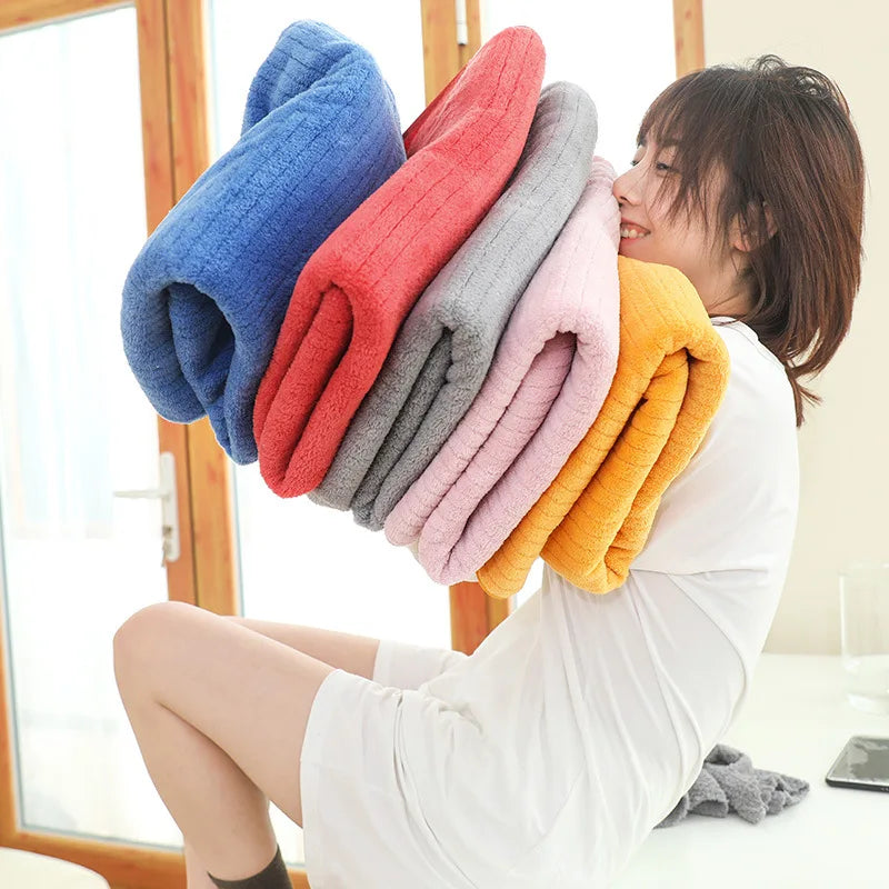 Une femme souriante tenant une pile de serviettes moelleuses colorées dans ses bras près d'une fenêtre.