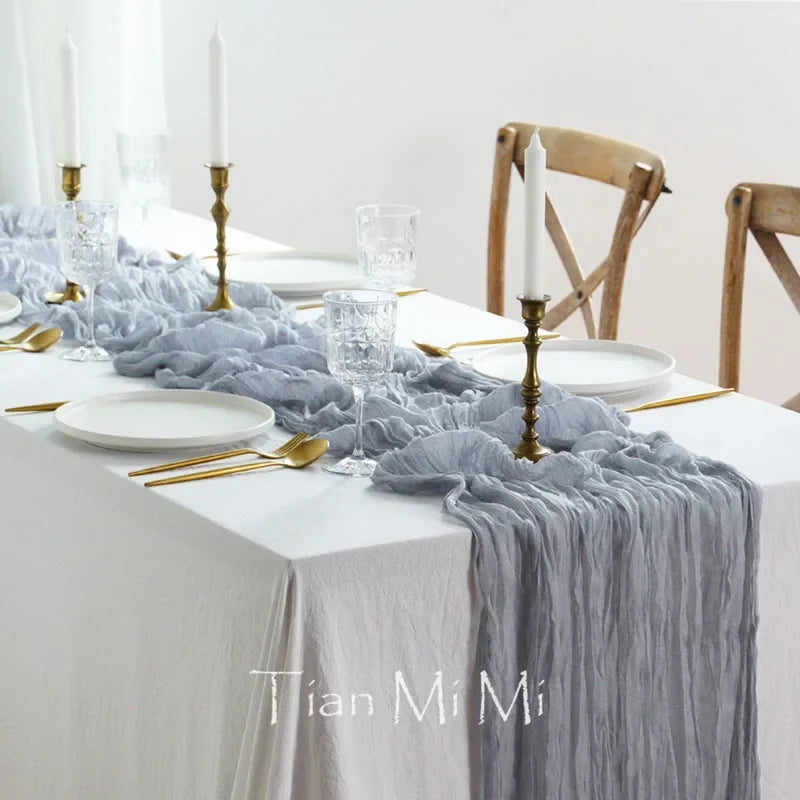 Table élégamment dressée avec nappe grise, bougies dorées, couverts dorés et verres cristallins, créant une ambiance sophistiquée et raffinée.