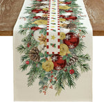Décoration de table de Noël avec guirlande de pins, boules rouges et dorées, pommes de pin et autres ornements festifs.