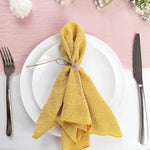 Une assiette blanche avec une serviette jaune pliée en forme de nœud sur un fond rose, accompagnée d'une fourchette et d'un couteau.