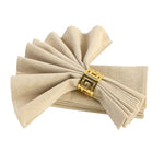 Des serviettes de table en lin beige attachées par une boucle décorative dorée.
