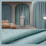Des rideaux bleus, suspendus à une fenêtre, apportant une texture textile douce et naturelle à la décoration intérieure, semblable à un papier peint de luxe. Les rideaux en polyester, un matériau naturel, créent une atmosphère chaleureuse et accueillante dans la pièce.