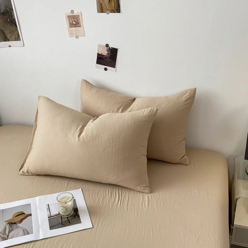 Un ensemble de coussins beiges sur un lit, décoré de quelques photos accrochées au mur, crée une atmosphère apaisante et intime dans cette chambre.