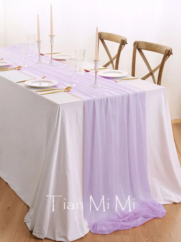 Une table de salle à manger élégante, parée de nappes blanches et de bougeoirs, avec des chaises en bois, pour une occasion spéciale.