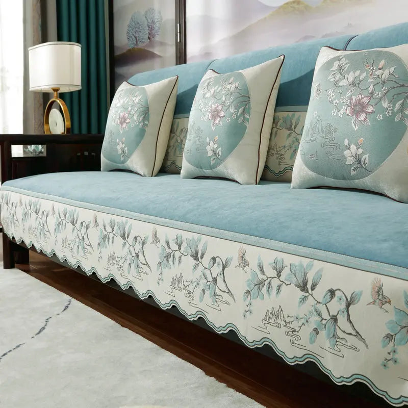 Un canapé confortable avec des coussins décoratifs orné de motifs floraux délicats dans des tons de bleu et de blanc, créant une atmosphère apaisante dans la pièce.