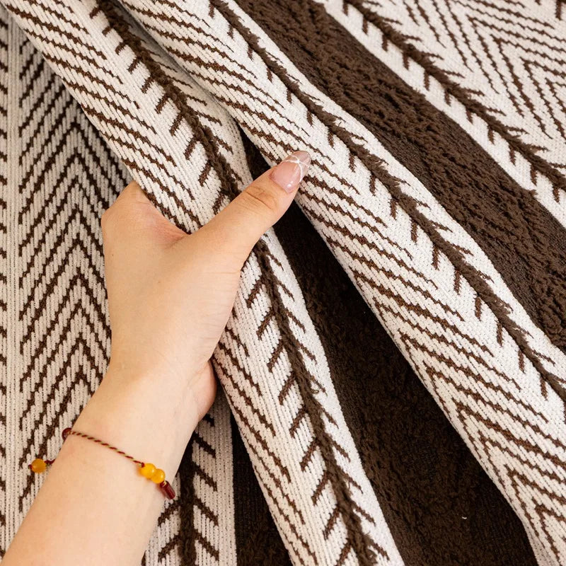 Une couverture ou un tapis tissé à motifs géométriques en blanc et marron, avec une main tenant un coin du tissu.
