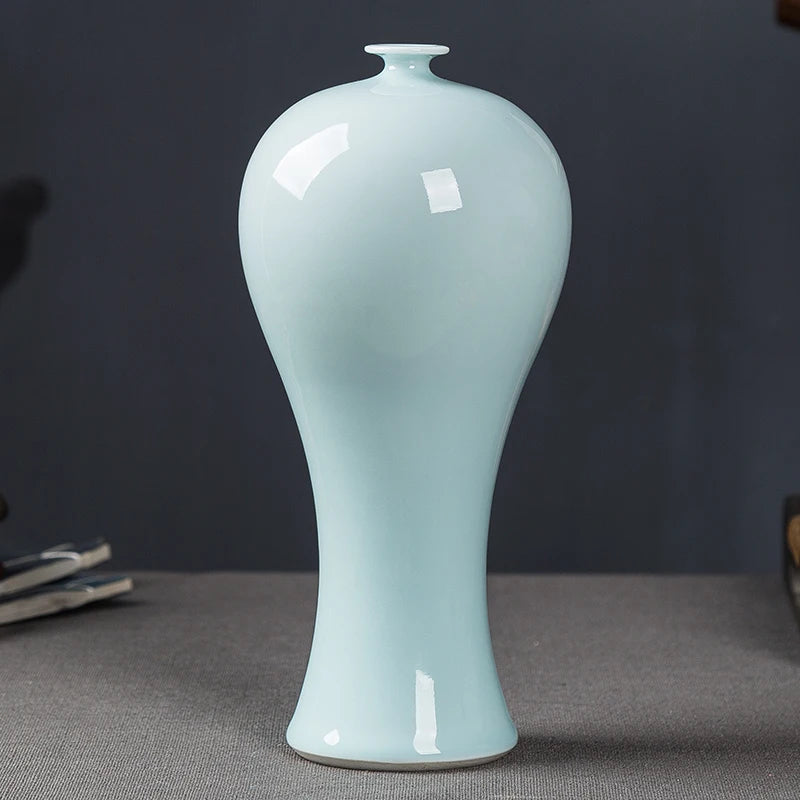 Un vase délicat et élégant en céramique de couleur vert clair, avec une forme galbée et un col étroit.
