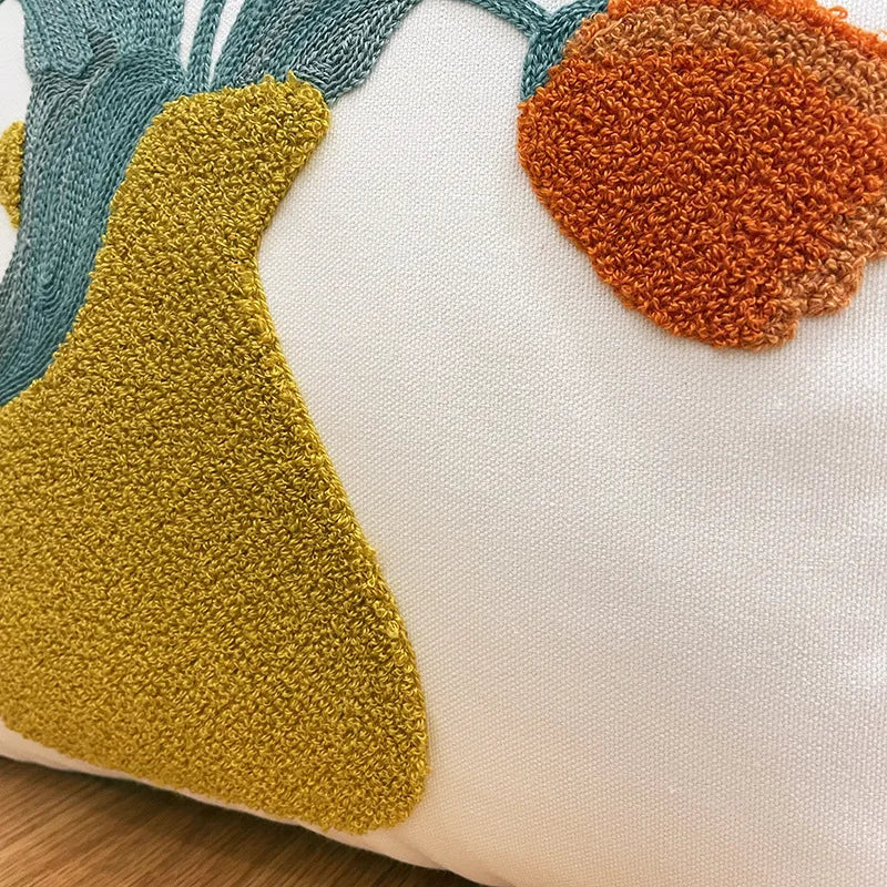 Coussin décoratif avec des motifs géométriques aux couleurs vives sur fond blanc.