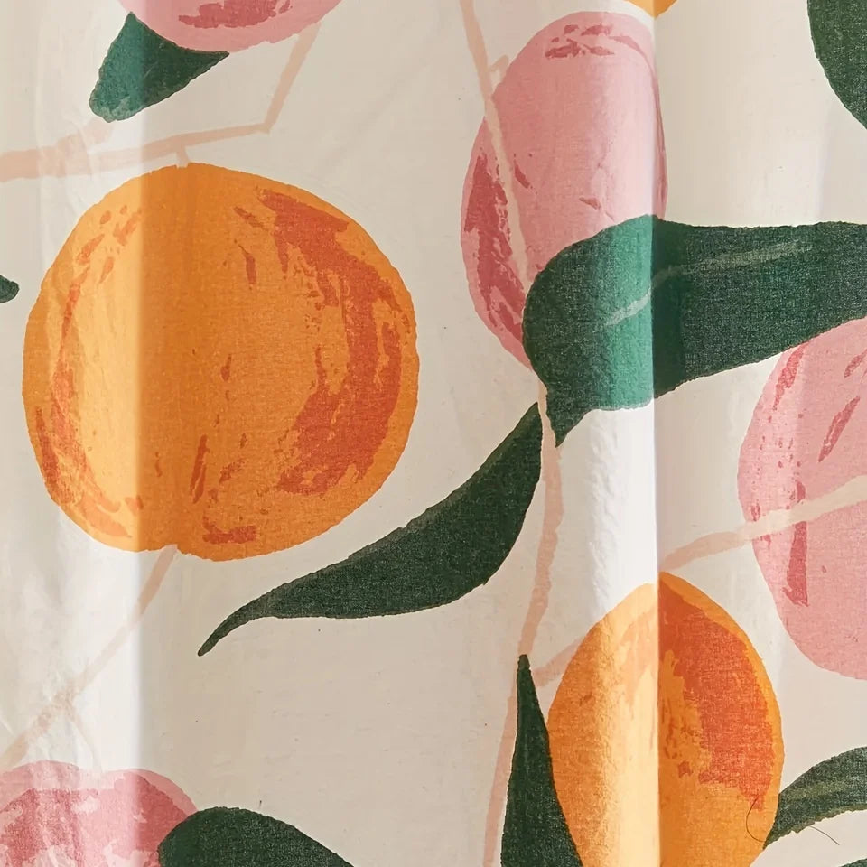 Rideau de douche orné de motifs de fruits oranges stylisés et de formes roses, sur un fond blanc, agrémenté de grandes feuilles vert foncé. 