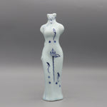 Représentation en porcelaine d'une forme féminine aux contours gracieux, décorée de motifs floraux et aquatiques dans des tons bleus, évoquant une vision apaisante et poétique.